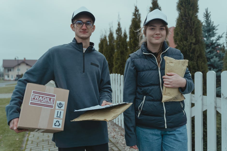 Two delivery workers carrying packages in a suburban neighborhood.